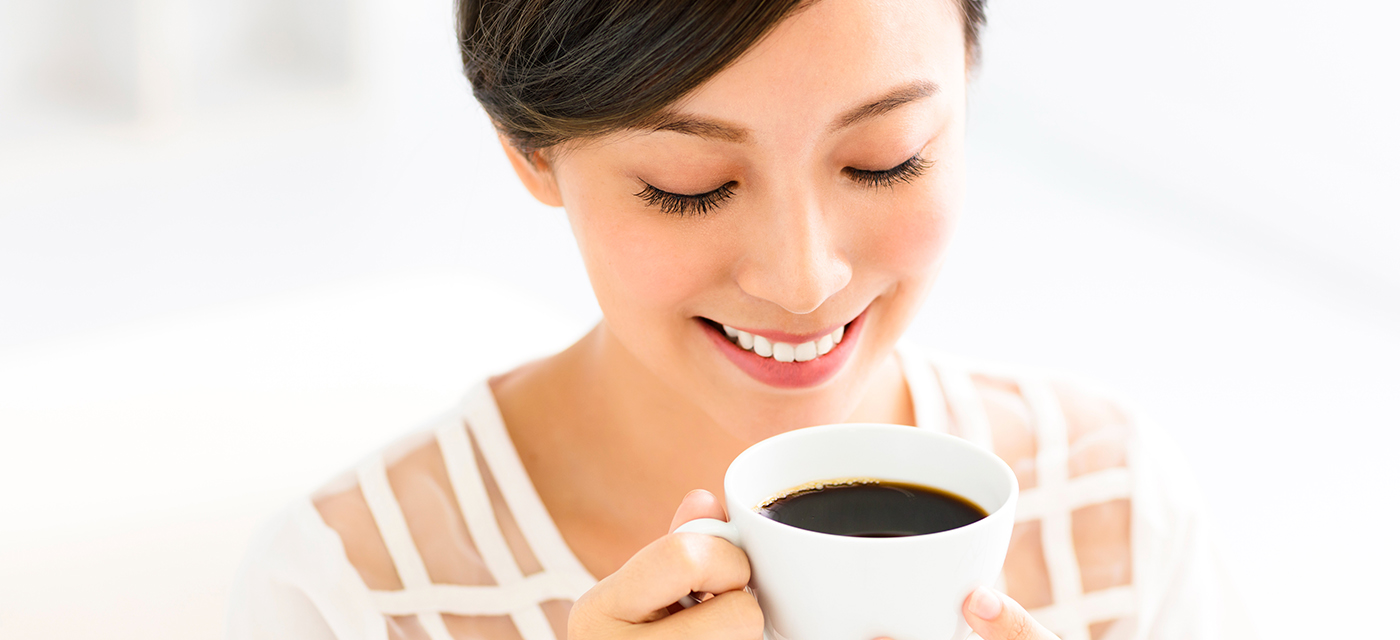 Mujer sonriendo mientras bebe una taza de café en el día internacional del café