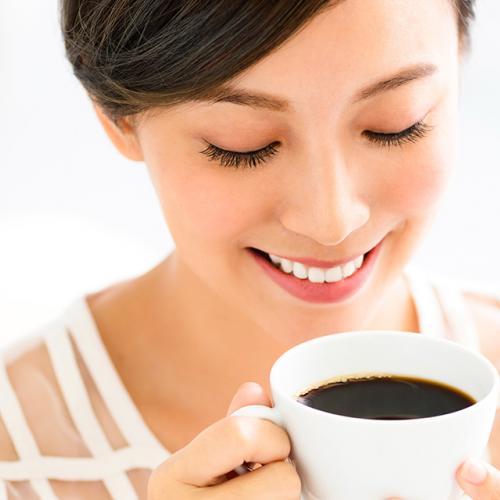 Mujer sonriendo mientras bebe una taza de café en el día internacional del café
